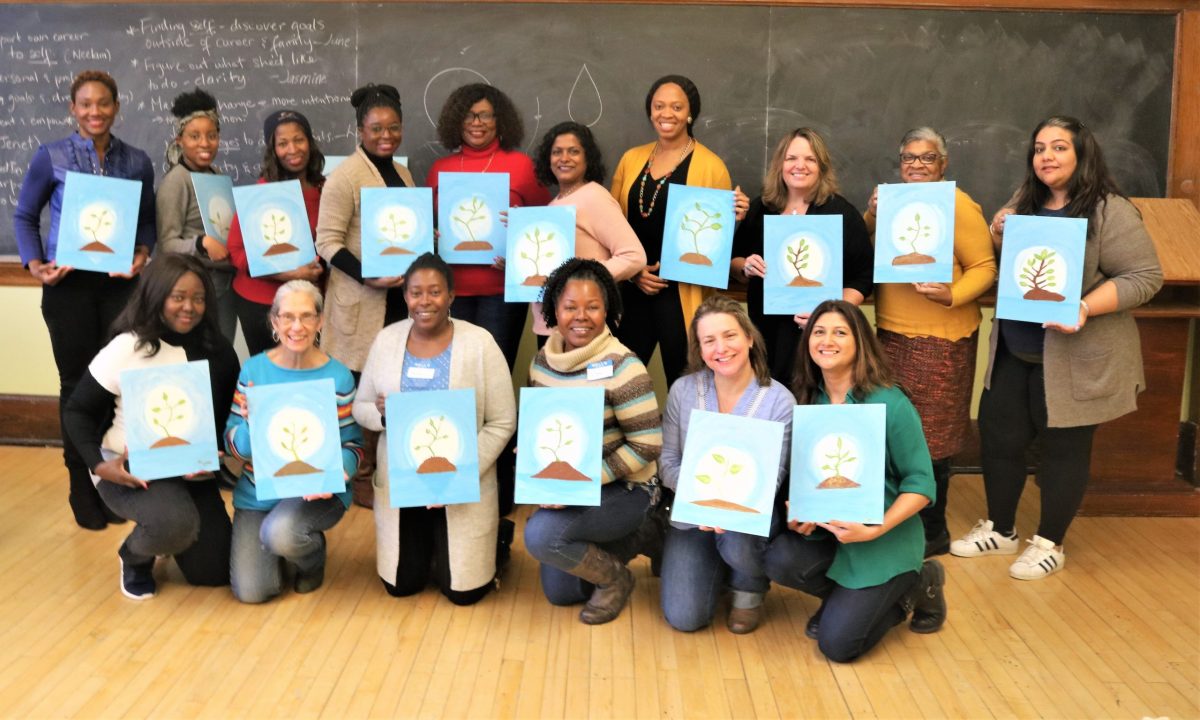Group of women holding up their painting at the Sip & Paint Visioning event 